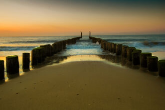 Zeeland Buhnen am Strand im Sonnenuntergang.