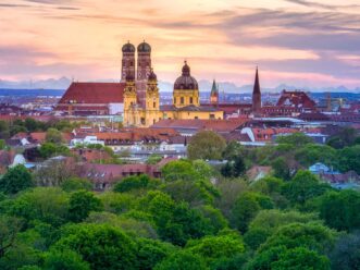 Luftbild München Skyline im Sonnenuntergang und Alpensicht.
