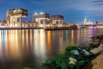 Kranhäuser in Köln in der Nacht mit Spiegelungen im Rhein